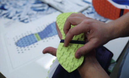 Close-up of a product designer examining an outsole with AdaptTrax technology. 
