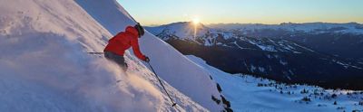 A person skiing down a mountain at sunset. 