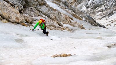 Image of an ice climber, head down, in the middle of a route.