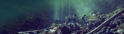 Hikers walking in front of a waterfall