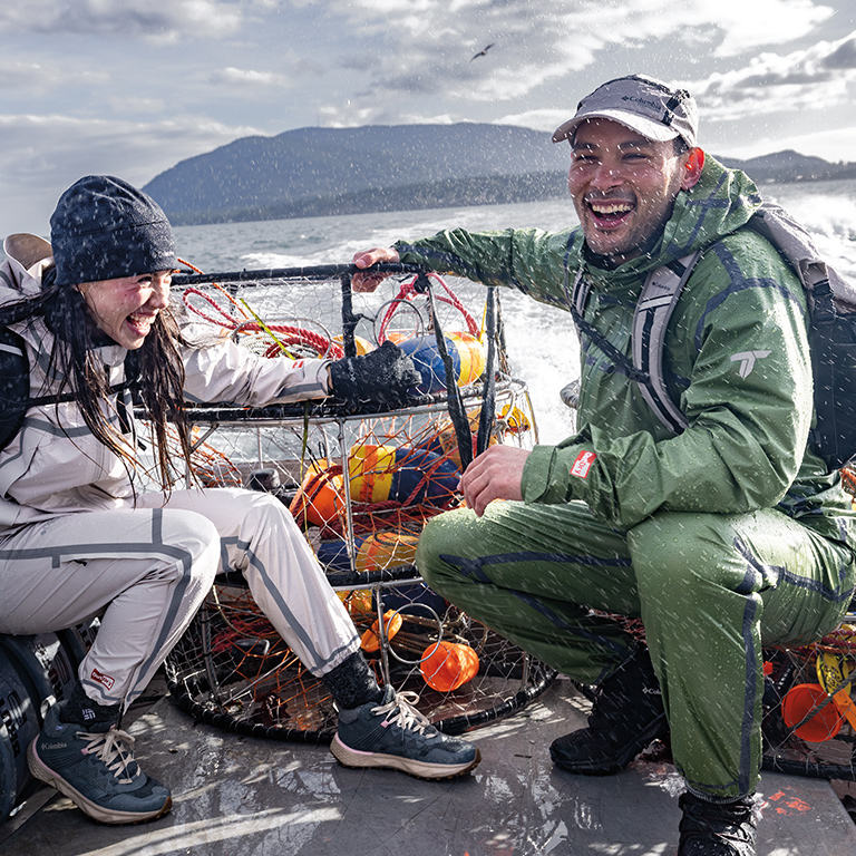 A couple on a fishing boat getting sprayed by water in their waterproof OutDry gear.
