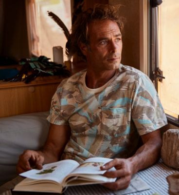 A man reads a book in a brightly lit dining nook.