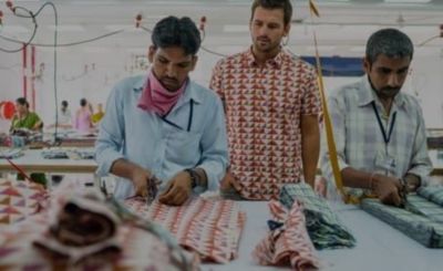 two men cut fabric for geo print button-up in a factory in India