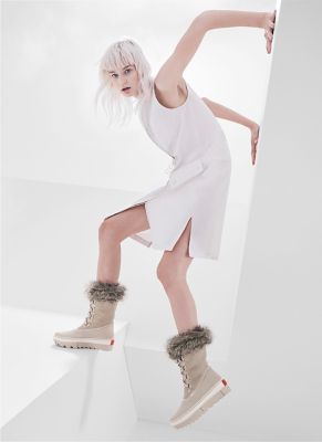 Woman posing wearing pair of Joan NEXT boots with futuristic background