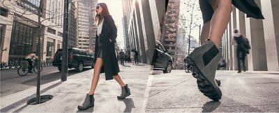 Left: Woman walking on city sidewalk in gray Joan Wedge Chelsea boots, Right: Close-up shot of woman's legs wearing gray Joan Wedge Chelsea boots