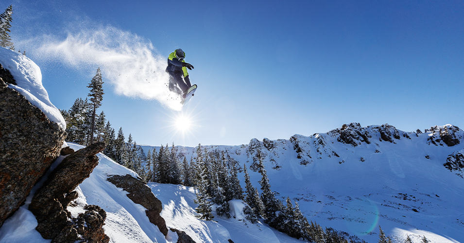 Curits Ciszek is snowboarding in a wintery mountain terrain. 