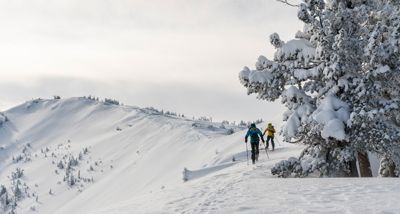 Two skiers skinning on the top a ridge, making way to their line.