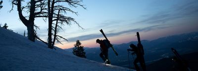 Group of three skiers skinning up in the backcountry at dusk