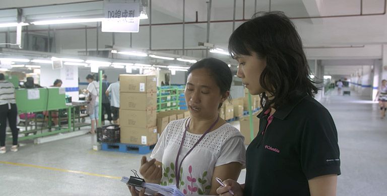 Columbia workers talking in a factory setting. 